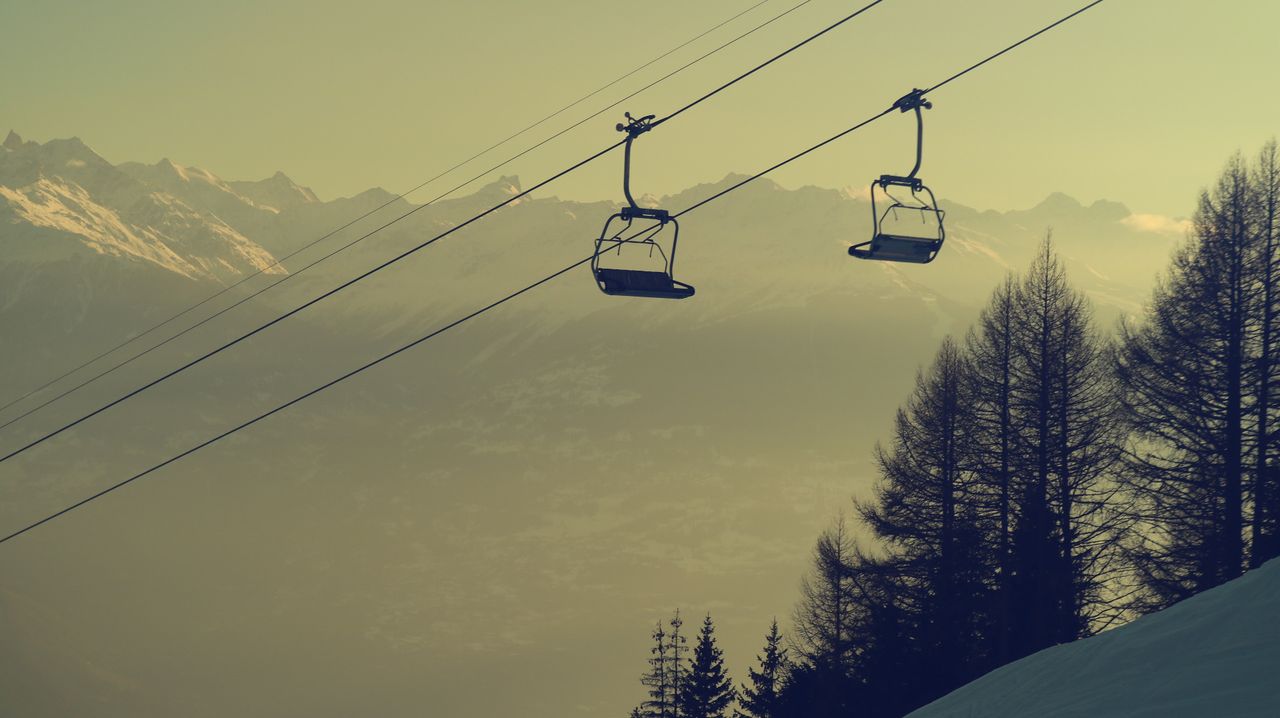 Télésiège au-dessus des sapins, montagnes dans la brume
